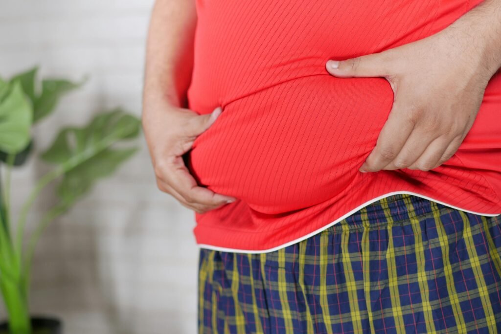 A man in a red shirt holding his midsection, focusing on health issues.